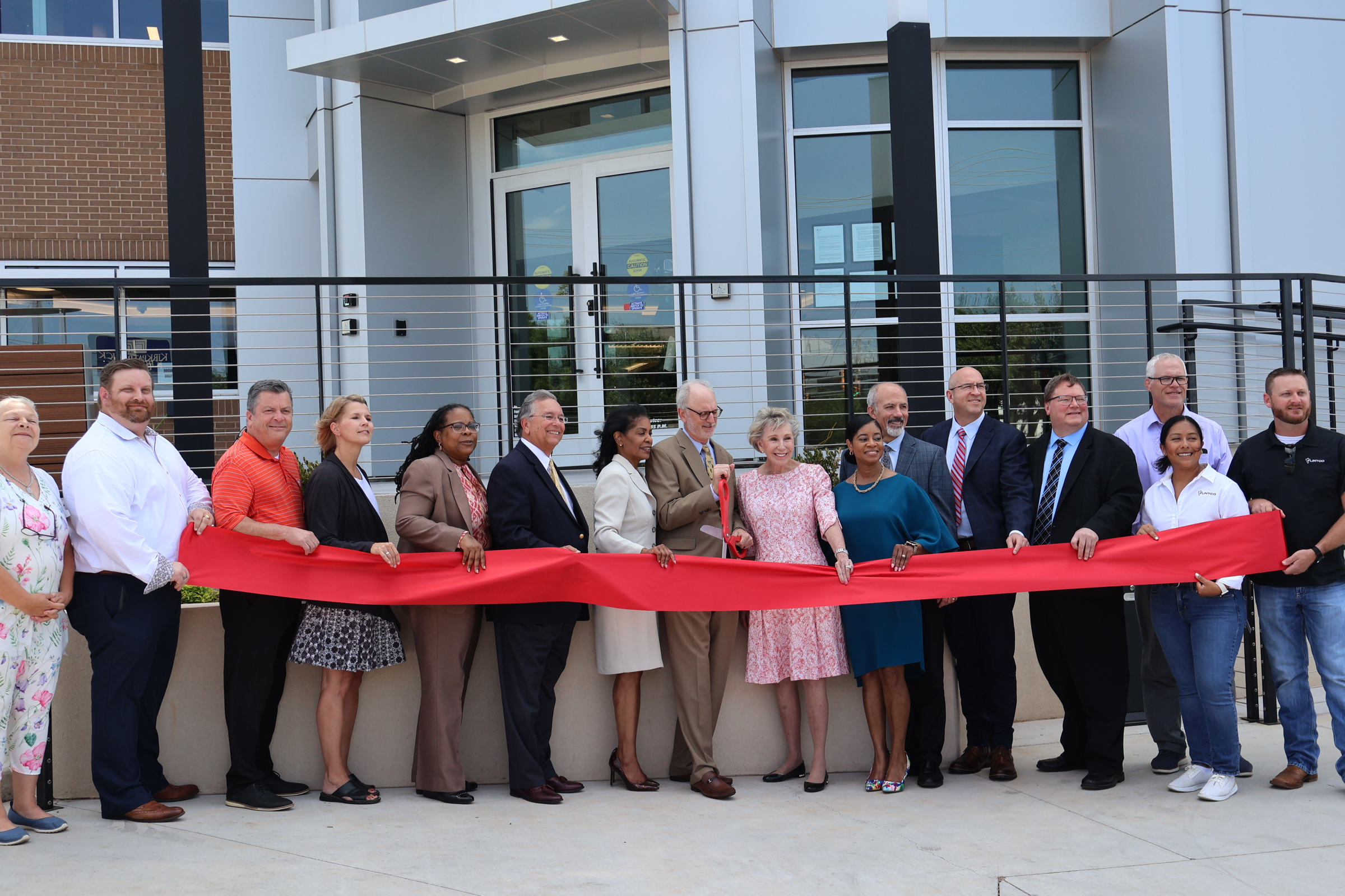 Representatives cut a red ribbon in front of the OHFA office building.,