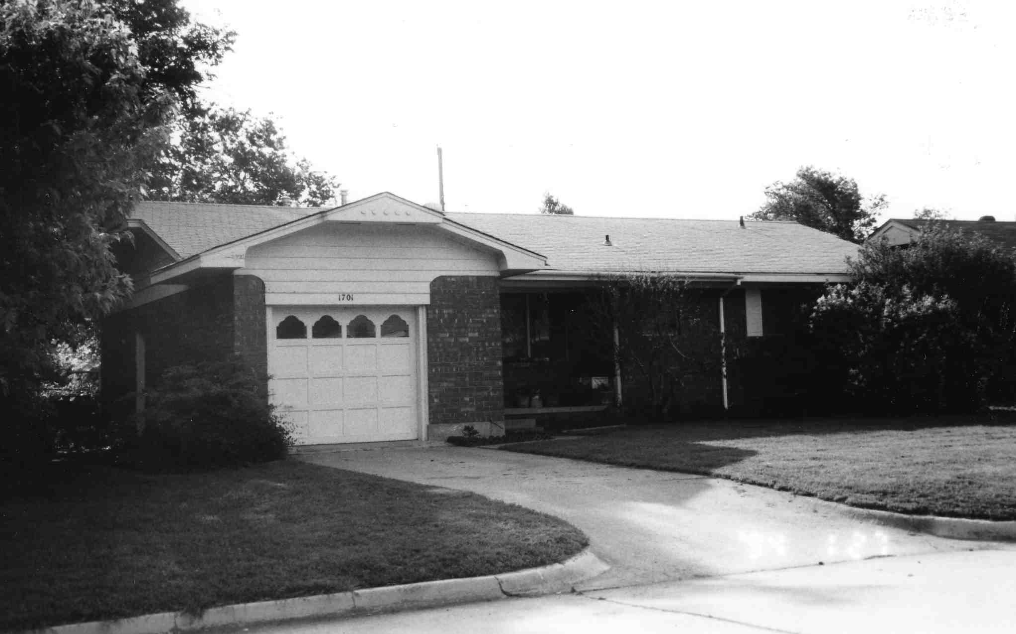 black and white photo of a small house with a one car garage