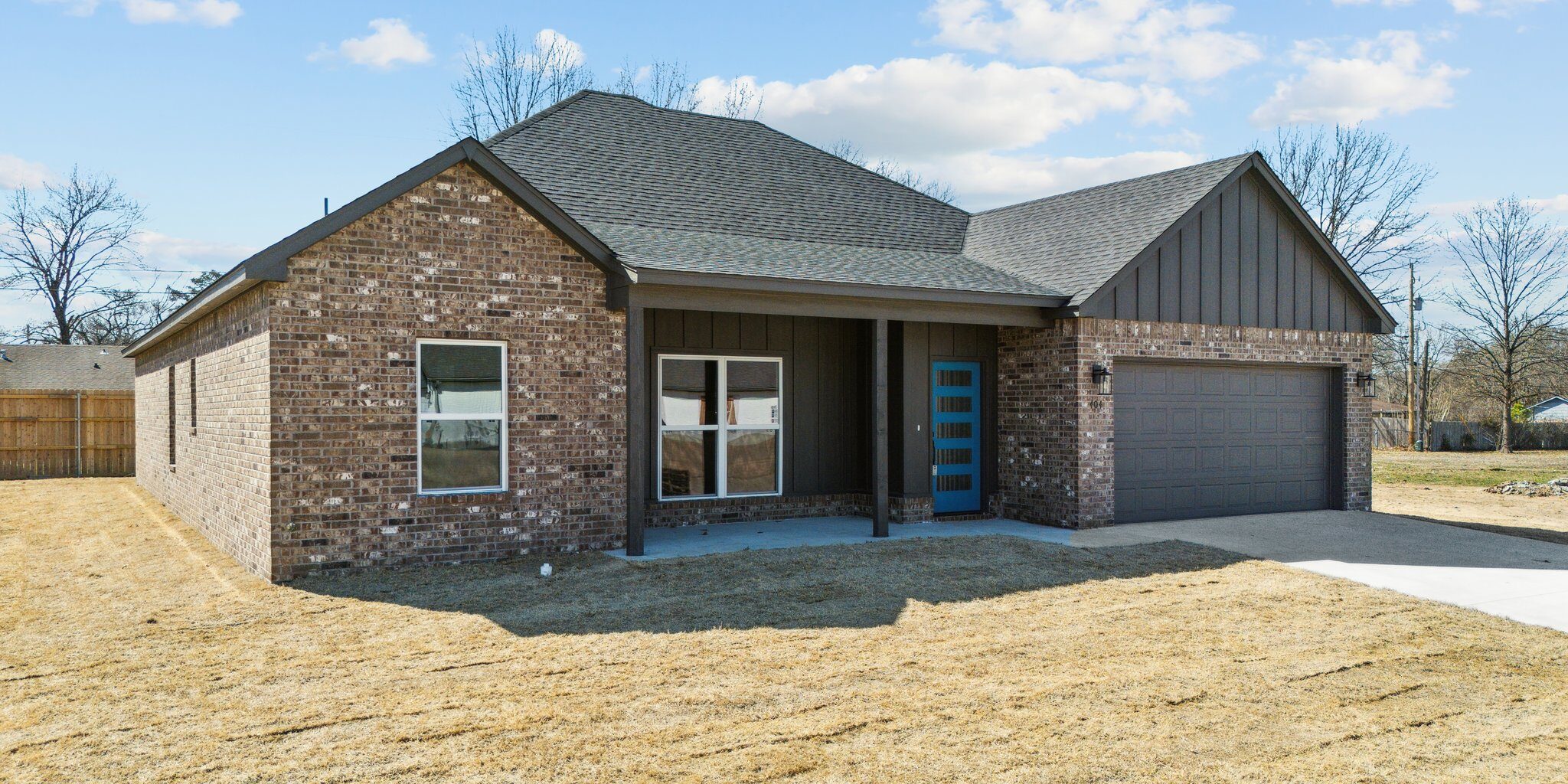 A brick home against a blue sky with clouds