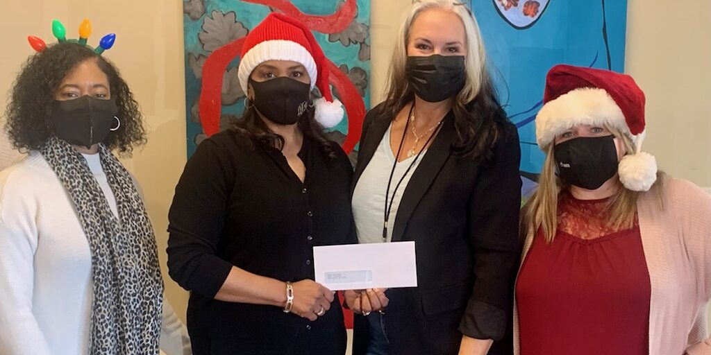 Trisha Bunce, development manager for Infant Crisis Services, accepts a donation from OHFA employees. Pictured: Tamara Steele, OHFA human resources director,  Deborah Jenkins, OHFA executive director,  Bunce, and Holley Mangham, OHFA communications manager.
